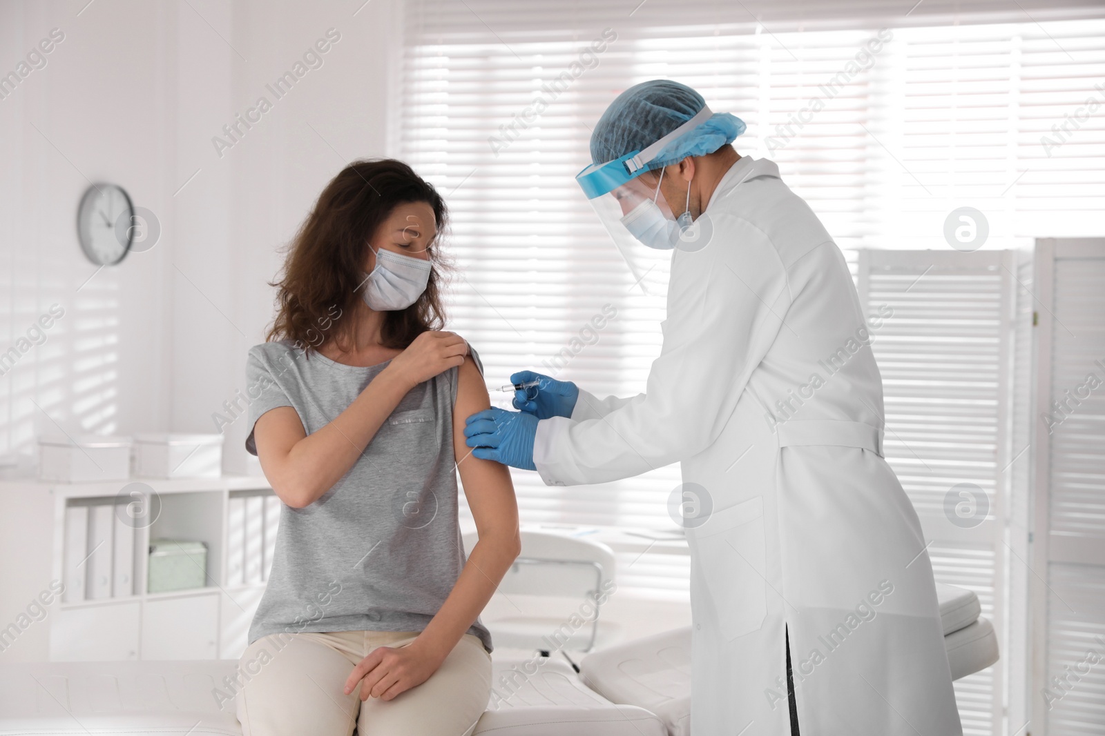 Photo of Doctor vaccinating mature woman against Covid-19 in clinic