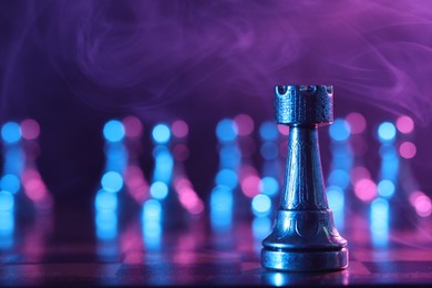 Photo of Rook on chessboard in color light, selective focus. Space for text