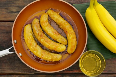 Delicious fresh and fried bananas with oil on wooden table, flat lay