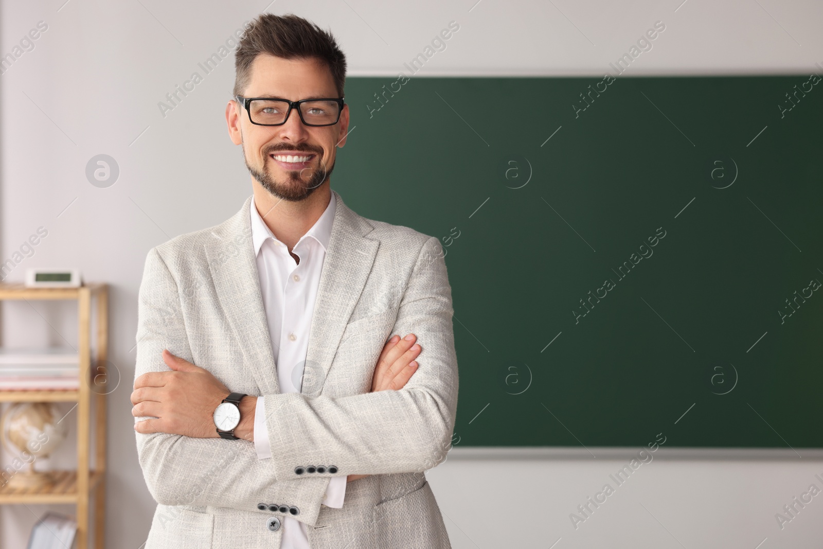 Photo of Happy teacher at blackboard in classroom. Space for text