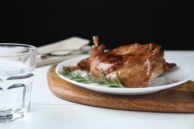 Photo of Tasty cooked rabbit meat with rosemary on white wooden table