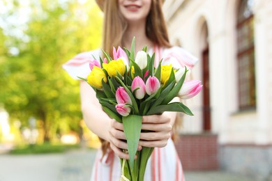 Photo of Teenage girl with bouquet of tulips on city street, closeup