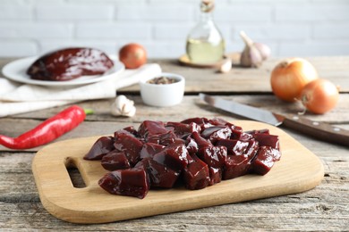 Photo of Cut raw beef liver and products on wooden table, closeup