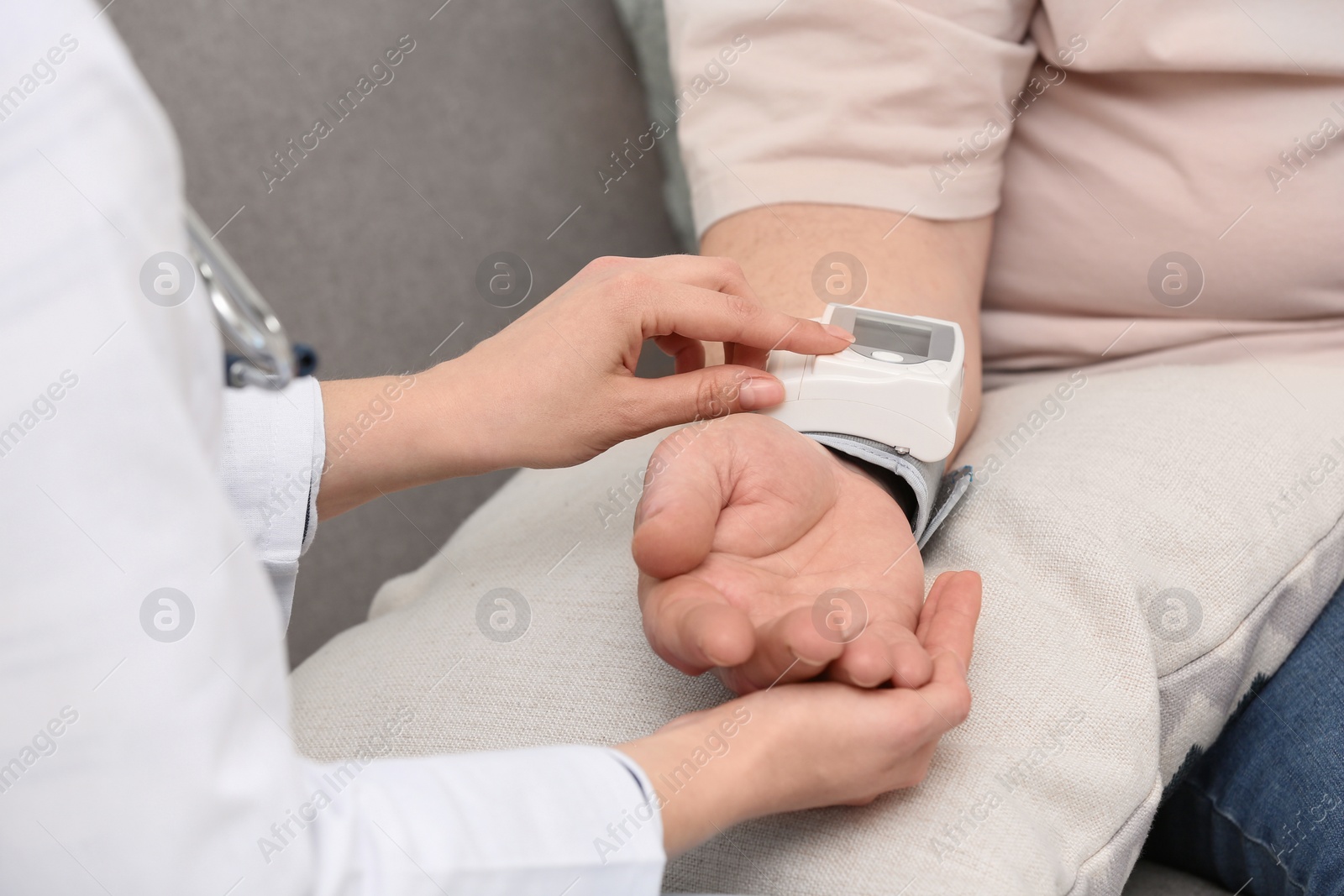 Photo of Nurse measuring blood pressure of elderly man against grey background, closeup. Assisting senior generation