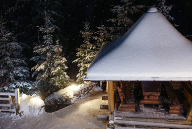 Photo of Snowy wooden pavilion in evening. Winter vacation