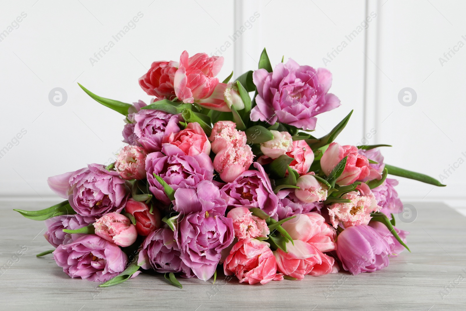 Photo of Beautiful bouquet of colorful tulip flowers on wooden table