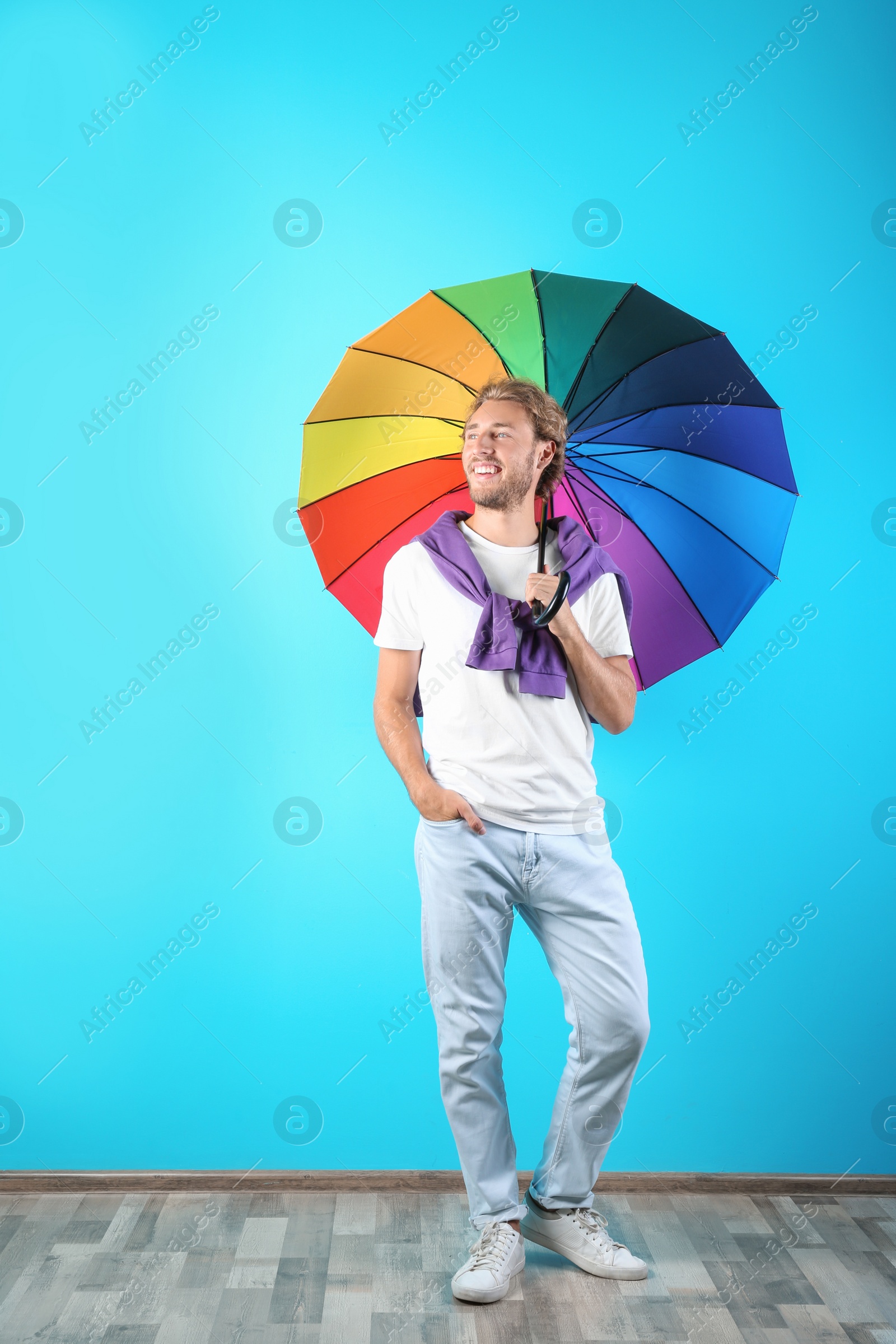 Photo of Man with rainbow umbrella near color wall