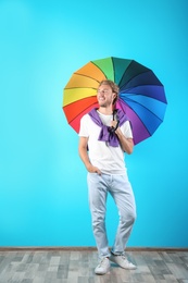 Man with rainbow umbrella near color wall