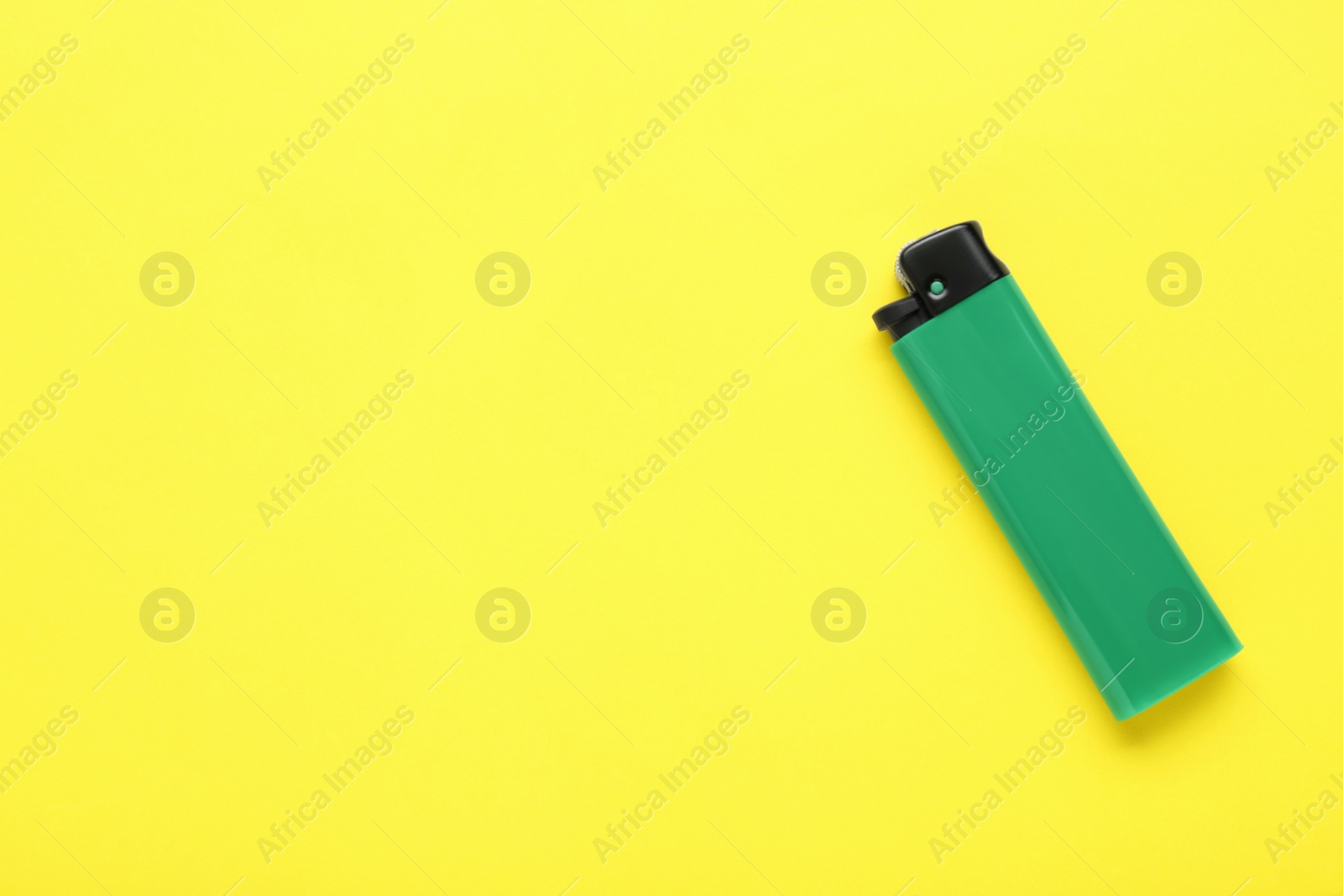 Photo of Stylish small pocket lighter on yellow background, top view. Space for text