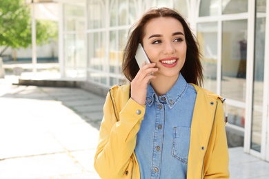 Photo of Young woman talking by phone outdoors on sunny day