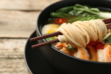 Photo of Bowl of delicious ramen with chopsticks on table, closeup and space for text. Noodle soup