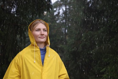 Young woman with raincoat in forest under rain