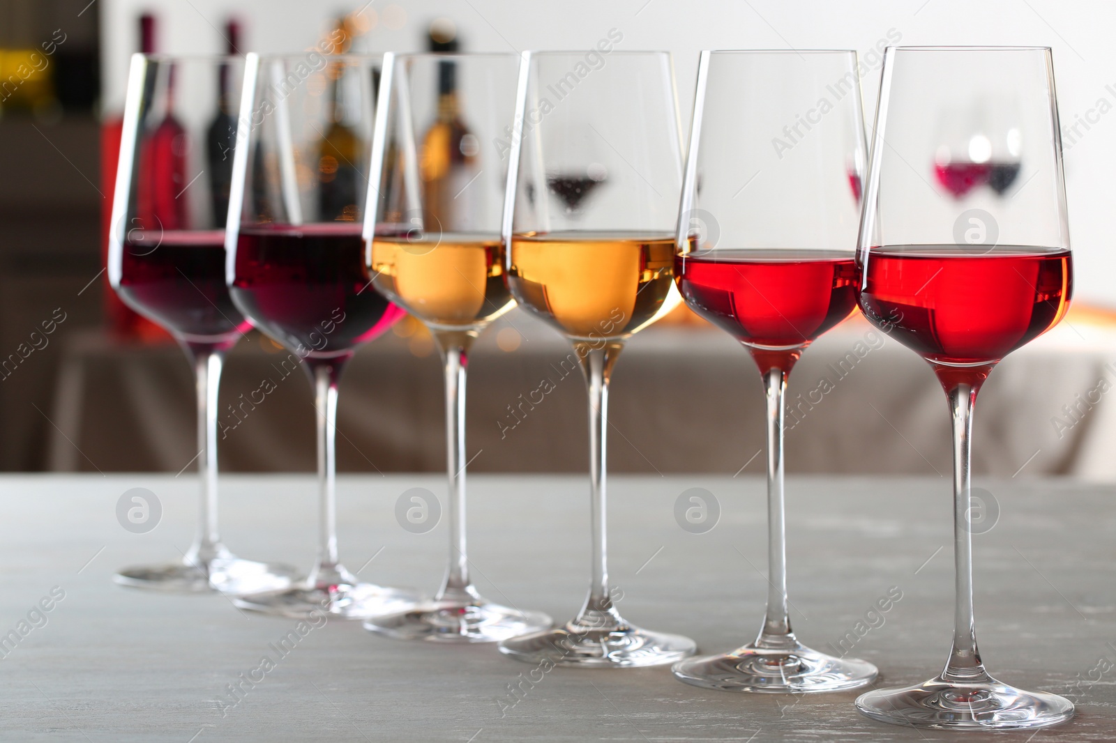 Photo of Row of glasses with different wines on table against blurred background