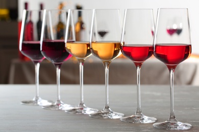 Row of glasses with different wines on table against blurred background