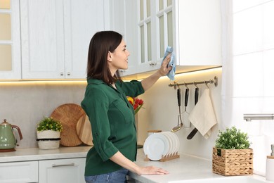 Woman cleaning furniture with rag in kitchen