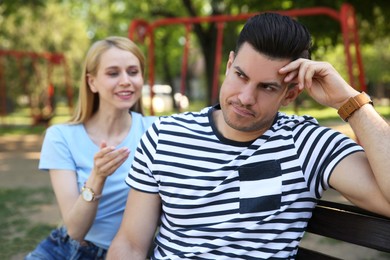 Photo of Displeased man ignoring overtalkative young woman during first date in park