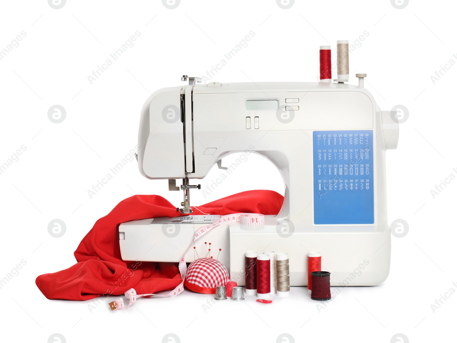 Photo of Modern sewing machine with red cloth and craft accessories isolated on white