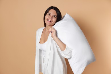 Photo of Happy young woman with soft pillow on beige background