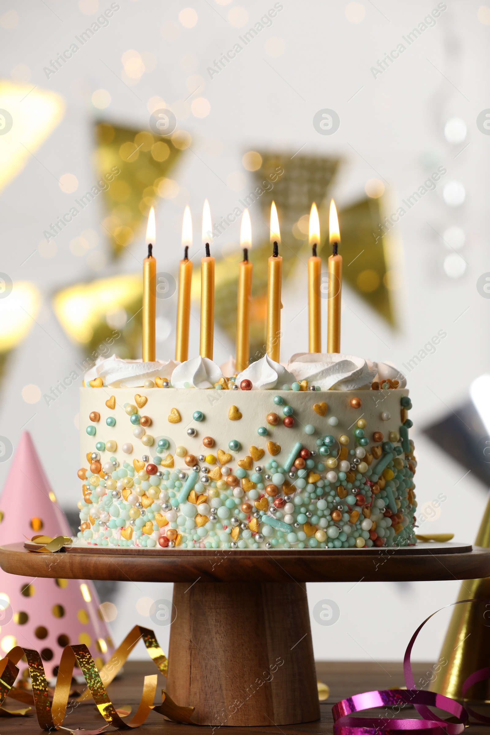 Photo of Beautiful birthday cake with burning candles and decor on wooden table