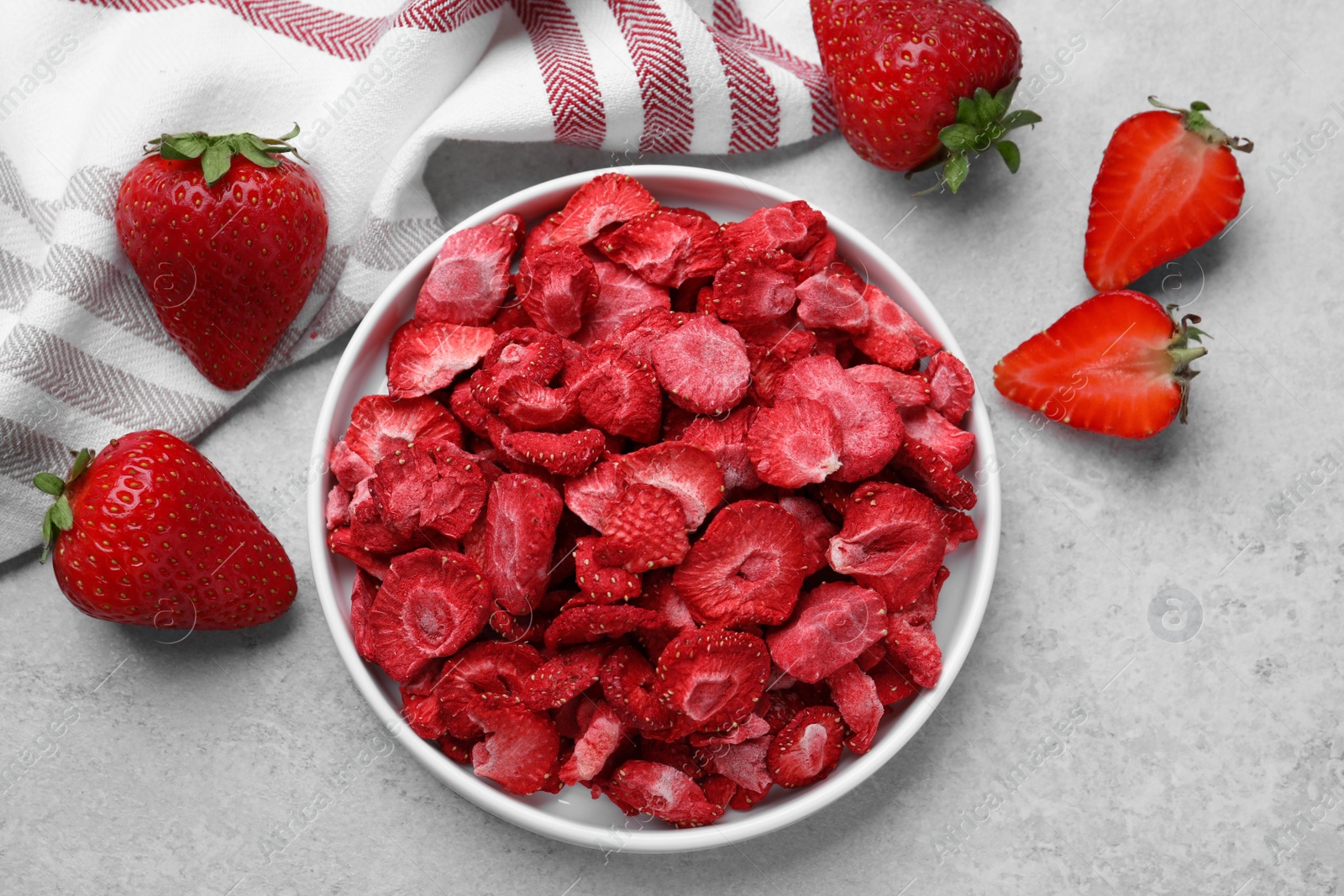 Photo of Freeze dried and fresh strawberries on light grey table, flat lay