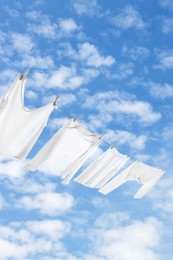 Image of Different clothes drying on washing line against sky