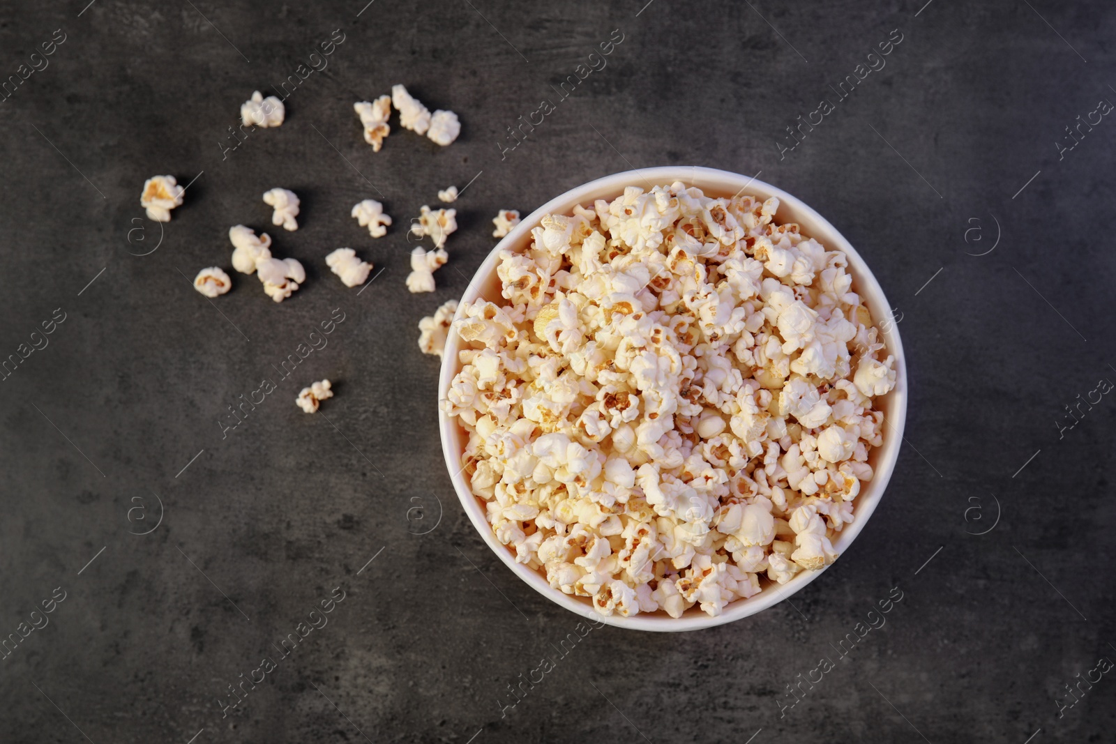 Photo of Paper bucket of tasty popcorn on grey background, top view