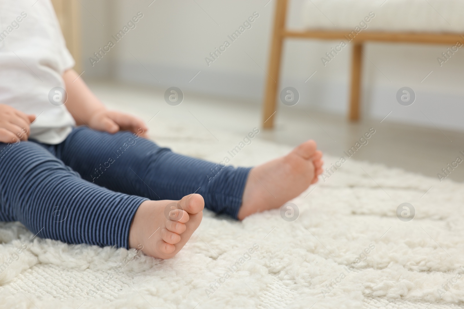 Photo of Baby sitting on soft carpet indoors, closeup. Space for text