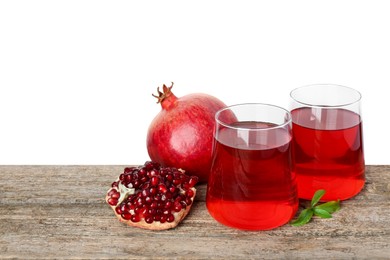 Photo of Refreshing pomegranate juice in glasses, leaves and fruits on wooden table against white background. Space for text