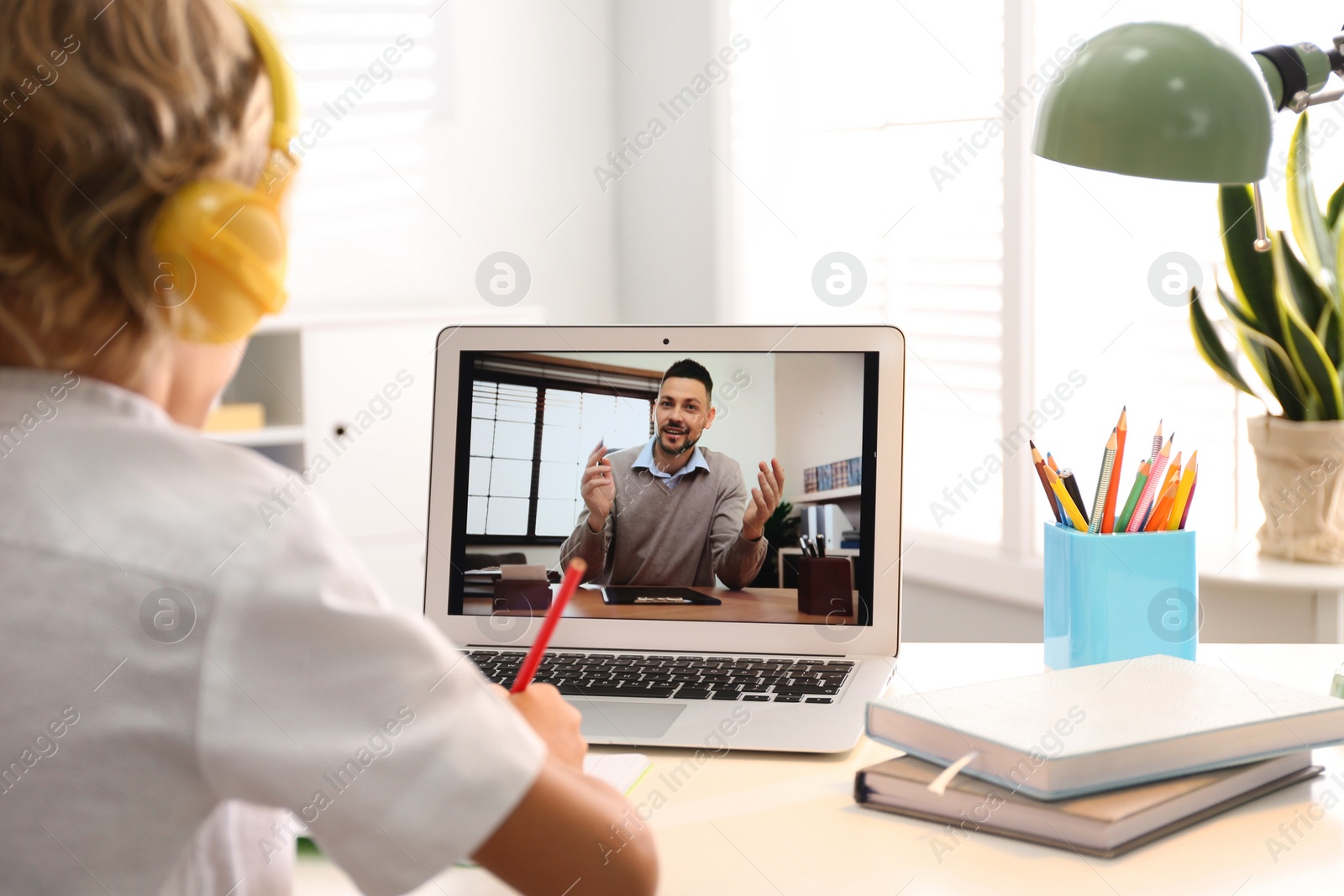 Photo of Little boy studying with teacher via video conference at home. Distance learning during COVID-19 pandemic