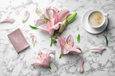 Photo of Flat lay composition with lily flowers, cup of coffee and notebook on marble background
