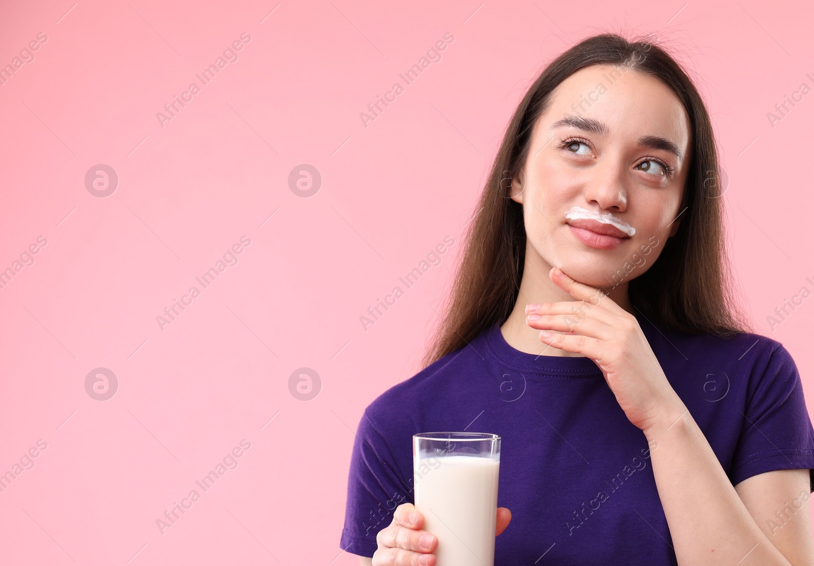 Photo of Cute woman with milk mustache holding glass of tasty dairy drink on pink background. Space for text