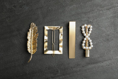 Photo of Beautiful different hair clips on black stone table, flat lay