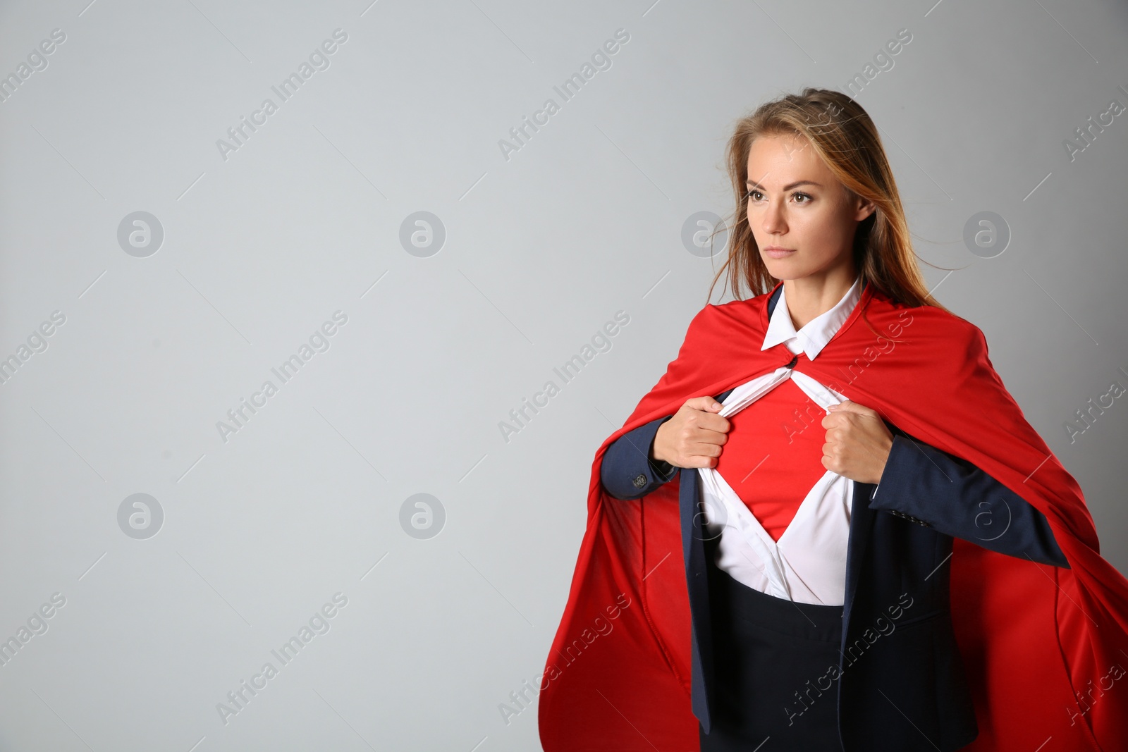 Photo of Confident businesswoman wearing superhero costume under suit on light grey background. Space for text