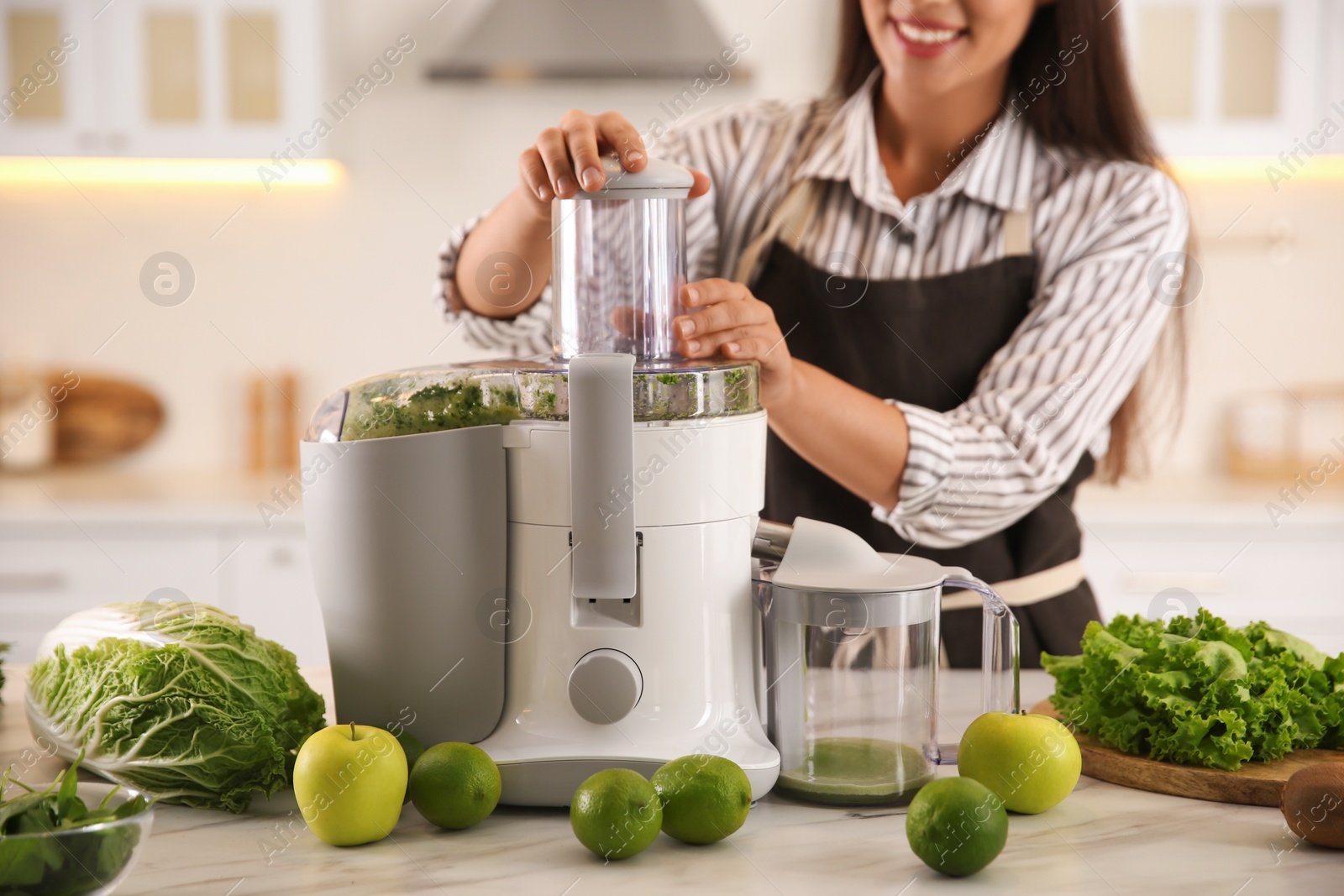 Photo of Young woman making tasty fresh juice at table in kitchen, closeup