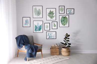 Photo of Beautiful paintings of tropical leaves on white wall in living room interior