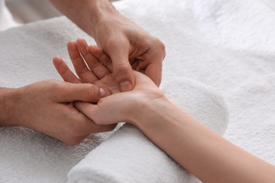 Woman receiving hand massage on soft towel, closeup