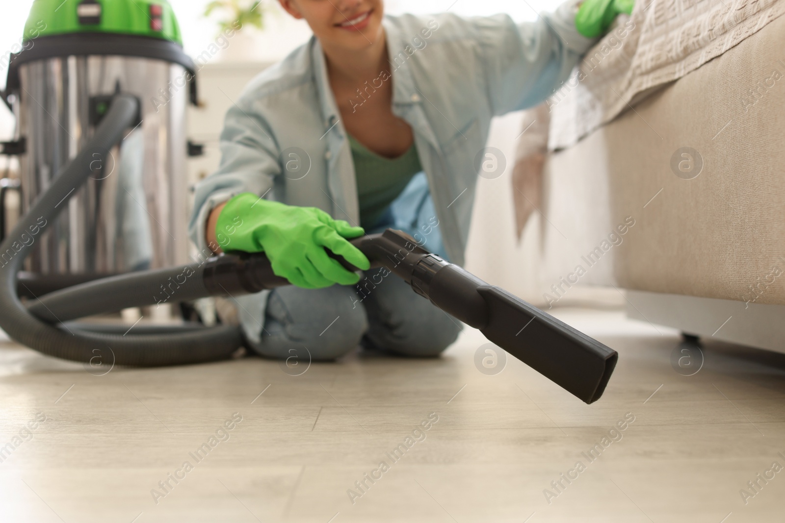 Photo of Young woman vacuuming floor in bedroom, closeup