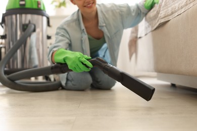 Photo of Young woman vacuuming floor in bedroom, closeup
