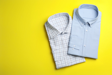 Photo of Stylish male shirts on yellow background, flat lay. Space for text