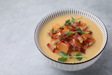 Photo of Delicious lentil soup with bacon and microgreens in bowl on gray table, closeup. Space for text