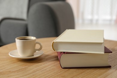 Photo of Books and cup of coffee on wooden table in living room