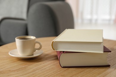 Books and cup of coffee on wooden table in living room