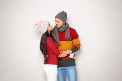 Young happy couple in warm clothes on light background. Christmas celebration