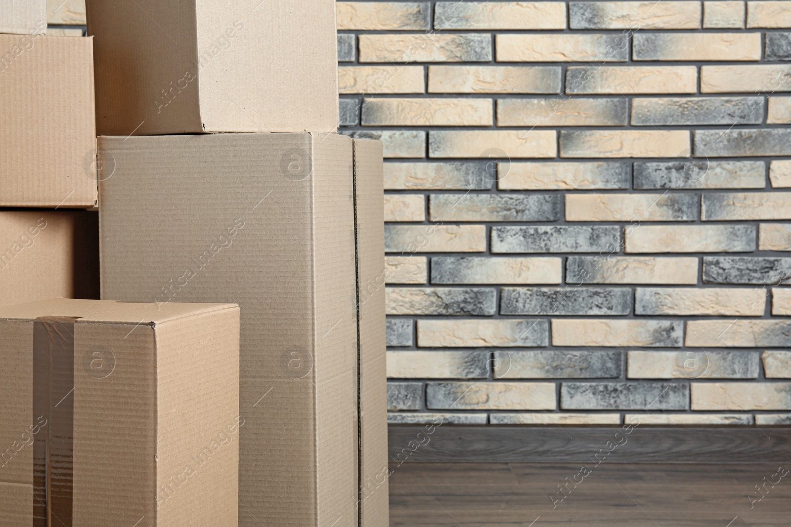 Photo of Pile of cardboard boxes near brick wall. Space for text