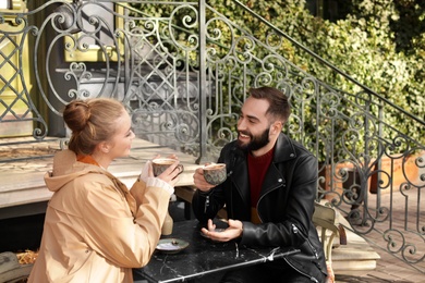 Lovely young couple enjoying tasty coffee at table outdoors