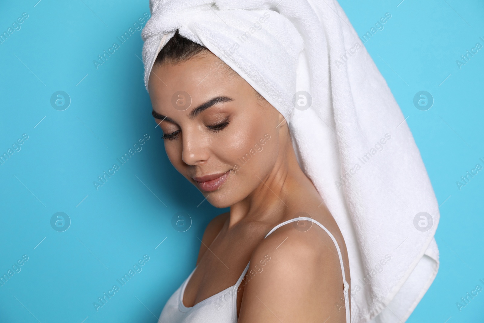 Photo of Beautiful young woman with towel on head against light blue background