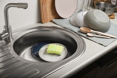 Washing plates and sponge in kitchen sink