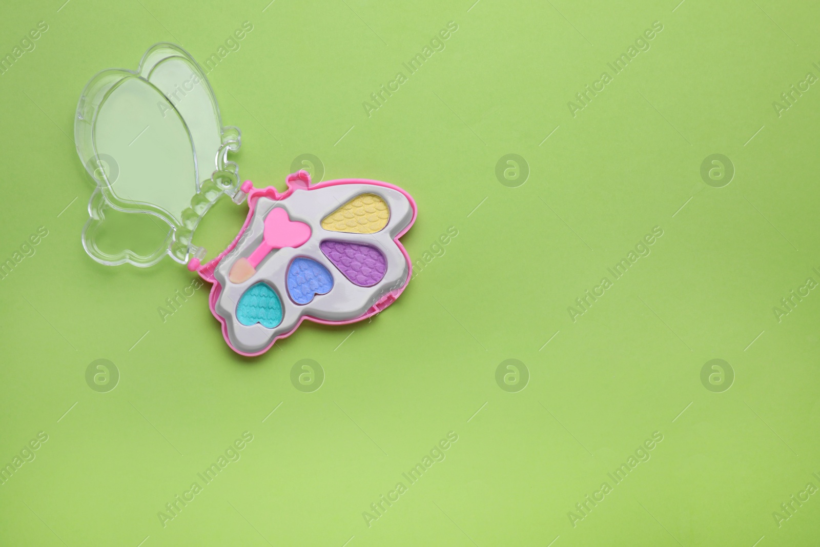 Photo of Decorative cosmetics for kids. Eye shadow palette on light green background, top view. Space for text