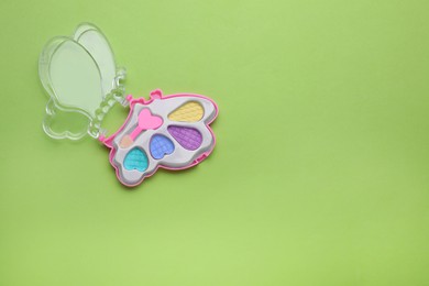 Photo of Decorative cosmetics for kids. Eye shadow palette on light green background, top view. Space for text