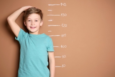 Photo of Little boy measuring his height on color background